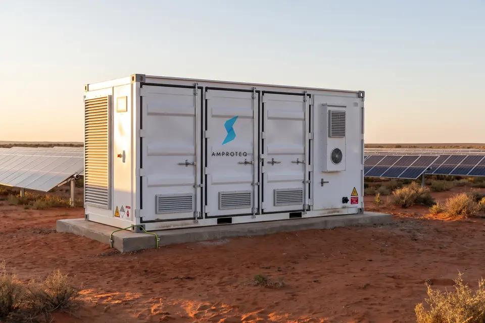 An AMPROTEQ A500 20 ft battery container and transformer skid at the edge of a solar plant